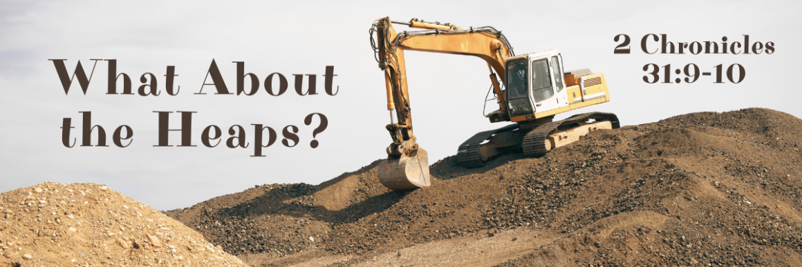 A large yellow excavator sits atop a heap of dirt and gravel under a clear sky. The text on the image reads 'What About the Heaps? – 2 Chronicles 31:9-10' in bold, brown letters.