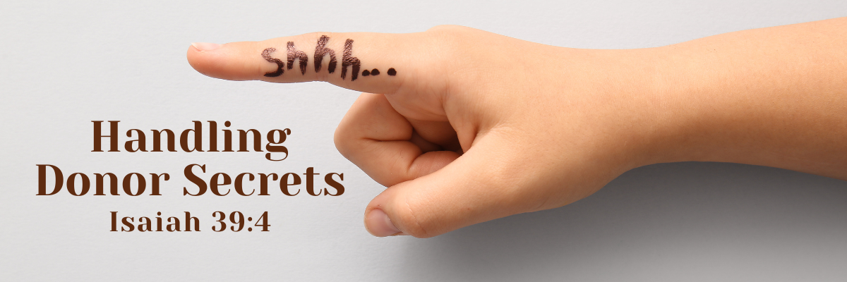 Close-up of a hand with a finger raised to the lips in a shushing gesture, with the word 'shhh...' written on the finger, next to the words 'Handling Donor Secrets – Isaiah 39:4' on a light background.