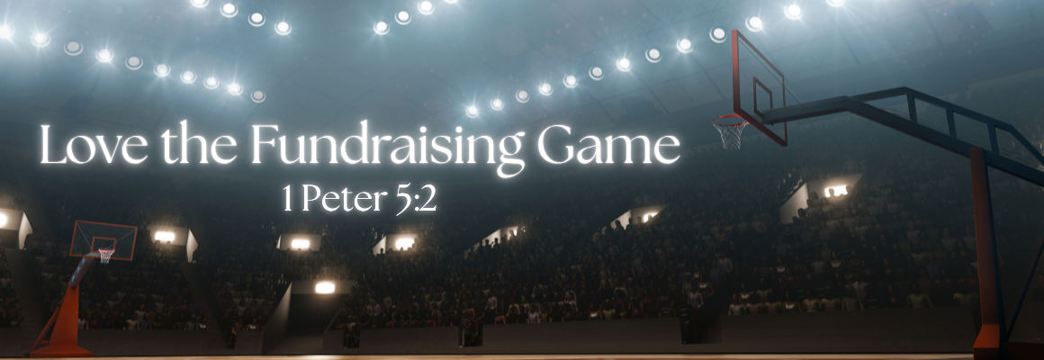 A dramatic wide-angle view of a packed basketball arena with bright overhead lights and two visible hoops, with the text Love the Fundraising Game and the scripture reference 1 Peter 5:2 in white lettering.